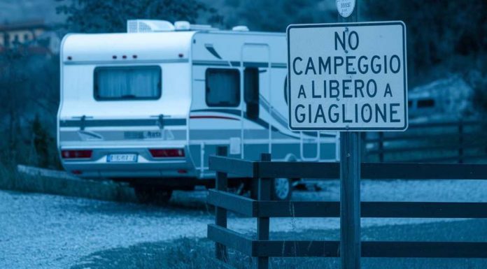 Campeggio a Giaglione: il sindaco dichiara guerra a camper, roulotte e tende per il 2025 una roulotte in un parcheggio a Valsusa, con un cartello che indica no campeggio a giaglione