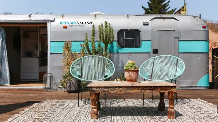 roulotte airstream vintage posizionata con un tappeto ed elementi di arredo